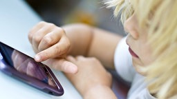 Das Beitragsbild des Dok5 "Das Fass der Pandora – Kinder und soziale Medien" zeigt ein Kleinkind von der Seite, dass auf einen Handybildschirm schaut und tippt.