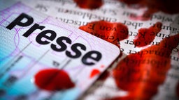 Das Beitragsbild des Dok5 "Back to zero. Journalisten im deutschen Exil" zeigt einen Presseausweis mit Blutstropfen