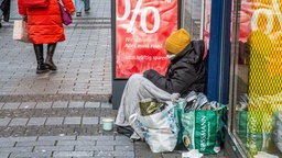 Das Beitragsbild des Dok5 "Angst haben fast alle" zeigt eine obdachlose Person in Decken gehüllt vor einem Schaufenster in der Fußgängerzone.