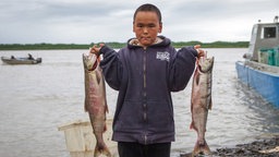 Das Beitragsbild des Dok5 "Fischen verboten" zeigt einen Jungen mit zwei gefangenen Lachsen am Yukon Rover in Alaska.