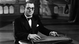 Das Beitragsbild des WDR3 Kulturfeature "Der vierte Mann" zeigt Anton Karas im Frack mit Fliege an seiner Zither