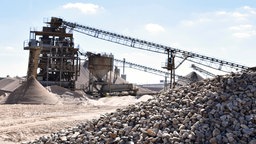 Kiesgewinnungsanlage mit Kieshaufen im Vordergrund