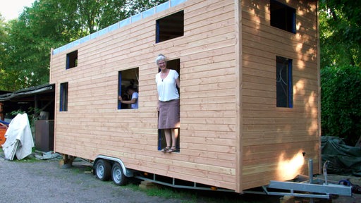 Eine Tiny House Besitzerin in ihrem mobilen Eigenheim auf Rädern 