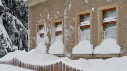 Die Fensterfront eines Hauses ist tief eingeschneit.