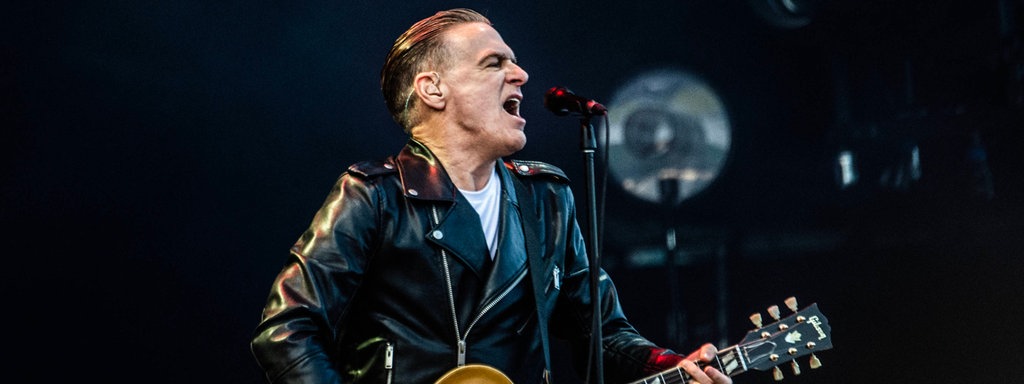 Bryan Adams singt und spielt Gitarre auf der Bühne