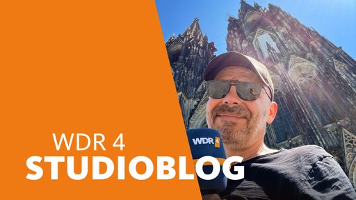 Lokalzeitreporter Peter Schultz steht mit Sonnenbrille und WDR 4-Mikro bei 35 Grad vor dem Kölner Dom