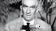 Szene aus dem Spielfilm "Fantomas": Inspektor Juve (Louis de Funès) hält einen Revolver in der Hand
