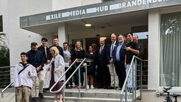 Das "Exile Media Hub Brandenburg" in Schmerwitz, Bewohner und Einwohner auf der Treppe vor dem Eingang. 
