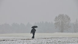 Das Beitragsbild des Dok5 Feature "Einsamkeit" zeigt einen einsamen Mann mit Regenschirm im Schneefall.