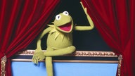 Kermit der Frosch öffnet den roten Vorhang eines Theaters