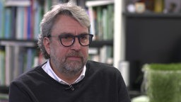 Portrait-Foto eines grauharigen Mannes in seinem Büro