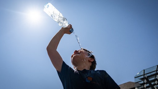 Ein Kind übergießt sich mit Wasser aus einer Flasche