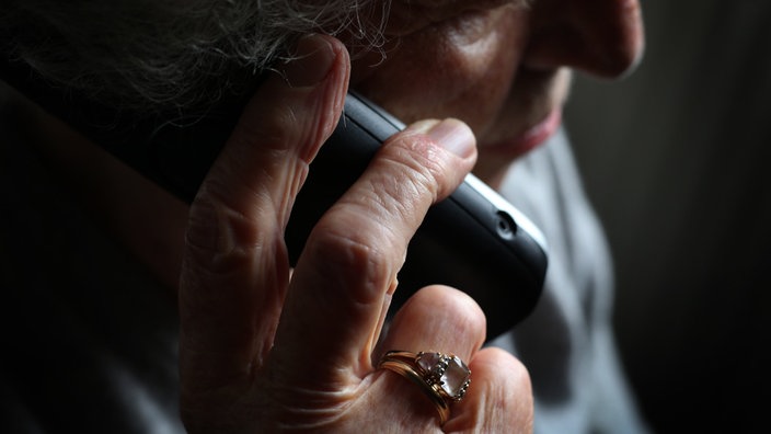 Ältere Frau nimmt einen Anruf am Festnetztelefon an