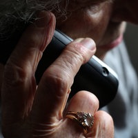 Ältere Frau nimmt einen Anruf am Festnetztelefon an