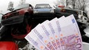 Geldscheine werden vor Schrottautos gehalten