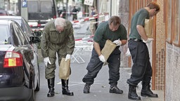 Polizisten untersuchen am 09.06.2004 in Köln-M lheim die Trümmer einer Bombenexplosion.