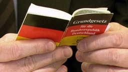 Hände halten Grundgesetz in Miniaturausgabe