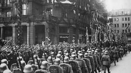 Eine Abteilung der deutschen Wehrmacht paradiert mit alten Regimentsfahnen aus dem Kaiserreich durch Köln.