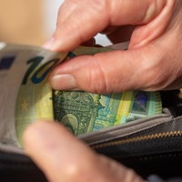 Eine ältere Hand greift in ein Portemonnaie