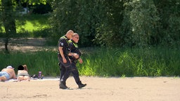 Zwei Kontrolleure laufen über den Sand 