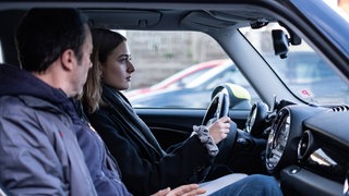 Eine junge Frau sitzt mit ihrem Vater im Auto