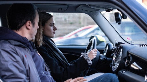 Eine junge Frau sitzt mit ihrem Vater im Auto