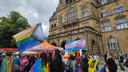 Menschen mit Pride-Flaggen stehen beieinander
