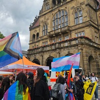 Menschen mit Pride-Flaggen stehen beieinander