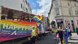 Eine Regenbogenflagge mit der Schrift "Happy Pride" hängt an einem Festwagen
