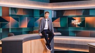 Louis Klamroth sitzend auf Pult im Studio