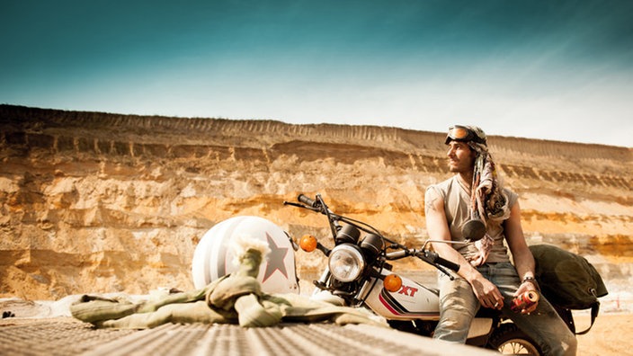 Der Biker lehnt sich an sein Motorrad