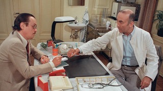 Dr. Dressler (Ludwig Haas, rechts) wird vom Kommissar (Horst D. Scheel) zu dem Überfall auf seine Praxis befragt.