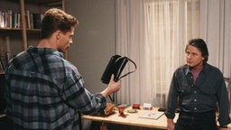 Jo zeigt Andy vorwurfsvoll eine Handtasche