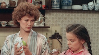 Verstimmt hilft Henny Schildknecht (Monika Woytowicz) ihrer Tochter Meike (Selma Baldursson) die Schultasche zu packen.