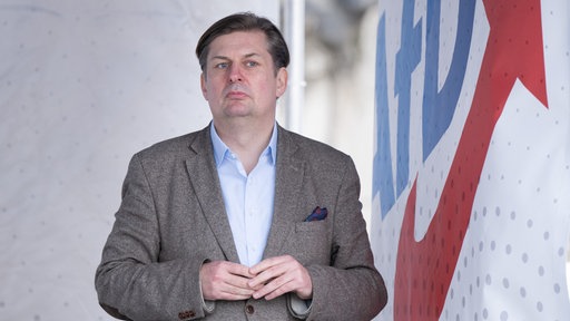 Das Bild zeigt Maximilian Krah vor einem AfD Logo.
