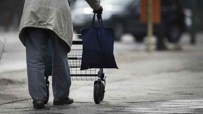 Eine ältere Person schiebt einen Rollator