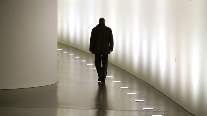 Der Schatten eines Mannes in einem beluchteten Gang