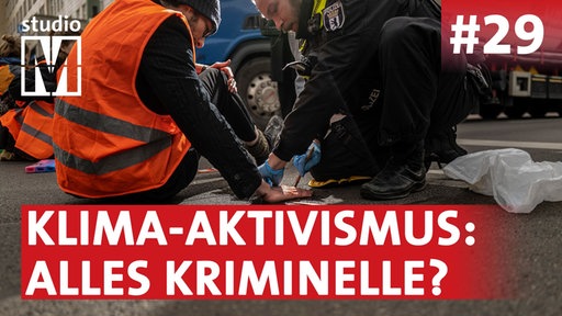 Polizist löst festgeklebte Hand eines Klimaaktivisten von der Straße