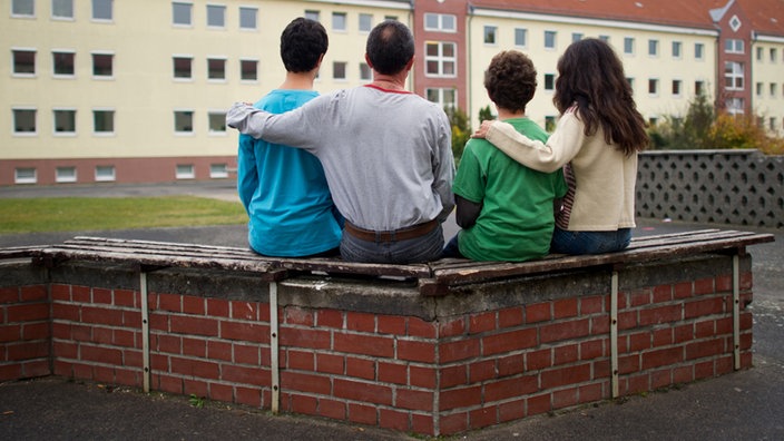 Eine syrische Familie sitzt vor einem Asylwohnheim 