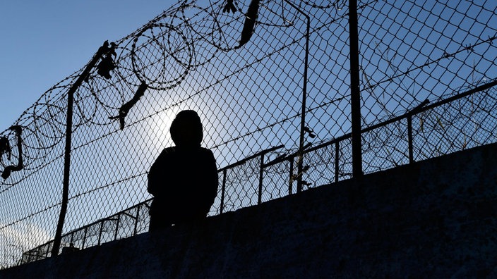 Ein Migrant sitzt neben einem Zaun des Flüchtlingslagers Moria.