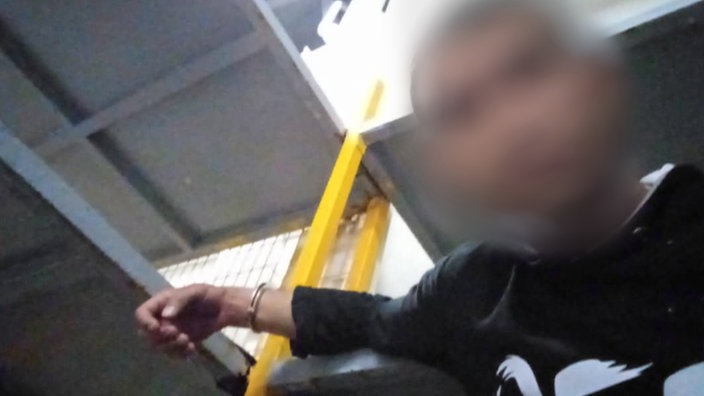 Angeketteter junger Mann auf einer Fähre. 