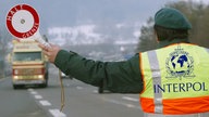 Mann mit Interpol-Warnweste hält Auto an