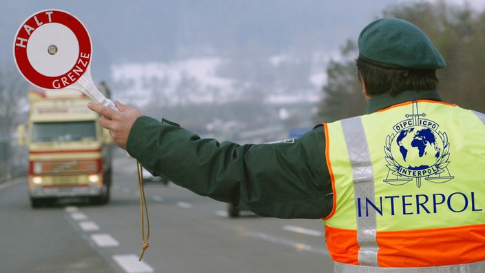 Mann mit Interpol-Warnweste hält Auto an