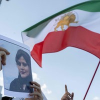 Bei einem Protest wird das Bild der verstorbenen Mahsa Amini hochgehalten, neben ihr die frühere iranische Flagge