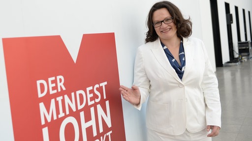 Andrea Nahles vor einem Schild mit der Aufschrift: Der Mindestlohn wirkt (2015)