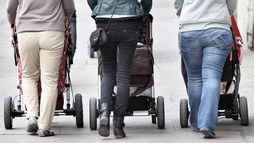 Drei Frauen von hinten mit Kinderwagen