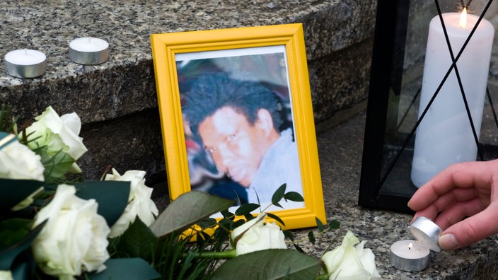 Ein Bild von Oury Jalloh, daneben Kerzen und Blumen, ähnlich einem Grab