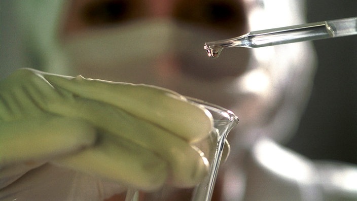 Laborantin mit Pipette und Glaskolben