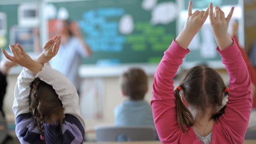 Zwei Schülerinnen melden sich während des Unterrichts in einem Klassenzimmer