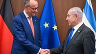 Das Bild zeigt Herrn Merz mit Herrn Netanjahu zusammen vor Flaggen.